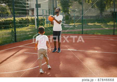 Black man with son playing basketball in basketball court together Black man with son playing basketball in basketball court together 87846668
