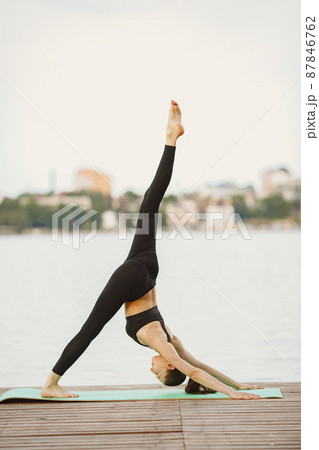 Woman practicing advanced yoga by the water 87846762