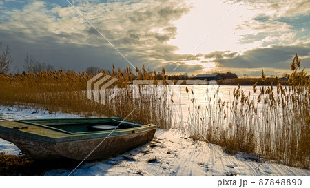 Heavenly winter clouds above a abandoned rural boat on lake Heavenly winter clouds above a abandoned rural boat on lake 87848890