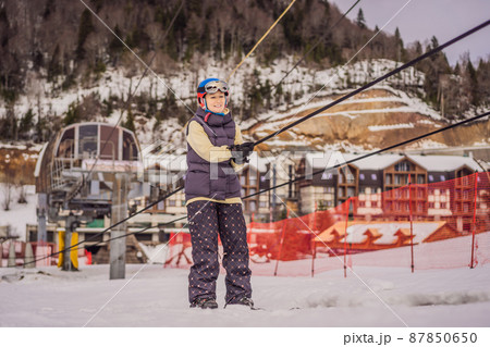 Woman skier climbs a mountain on a ski lift for beginners 87850650