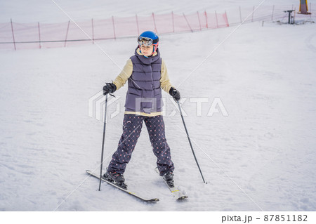 Woman learning to ski. Young woman skiing on a snowy road in the mountains 87851182