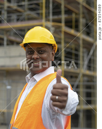 Positive, smiling and successful Indian construction worker posing looking at the camera and showing a thumbs up gesture Positive, smiling and successful Indian construction worker posing looking at the camera and showing a thumbs up gesture 87854089
