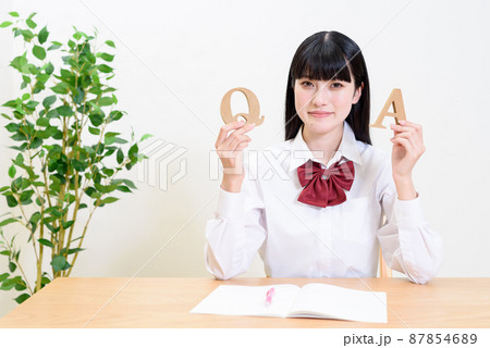 室内で勉強する女子高校生　QとAのアルファベットを持つ女性　疑問と答え 87854689