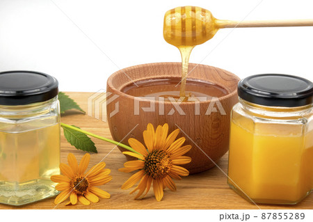 fresh floral honey dripping from a spoon into a wooden plate on a white background 87855289