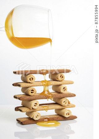 Fresh flower honey flows and drips onto herdry crispy cookie sticks. Dessert snack food. Fresh flower honey flows and drips onto herdry crispy cookie sticks. Dessert snack food. 87855994