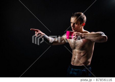 Man on black background keeps dumbbells pumped up in fitness active biceps arm muscular exercise athletic heavy, healthy weightlifting. Young skin metal, gym fit In the athlete's pink cup he smiles 87856116
