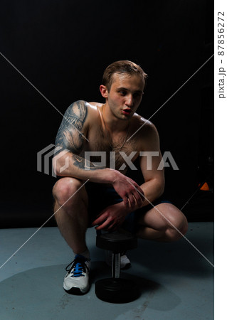 Man on black background keeps dumbbells pumped up in fitness active biceps black, body weight man bodybuilder hand, healthy weightlifting. Young handsome adult, guy fit 87856272
