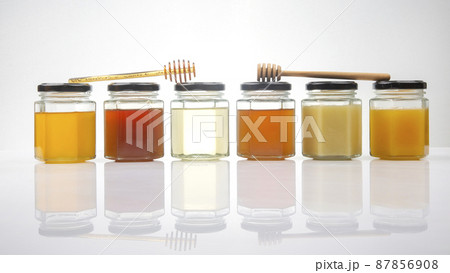 Hexagonal jars with different types and colors of fresh flower honey and a honey spoon 87856908