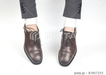 Classic brown shoes worn on the hands on a white background 87857255