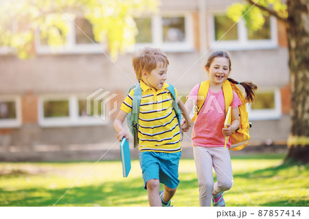 Boy and girl running to the school Boy and girl running to the school 87857414