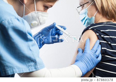 Female medical worker giving injection shot to elderly woman,doctor or nurse holding syringe with needle 87860378