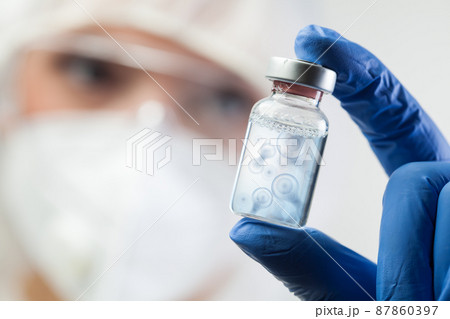 Cell division process conceptual illustration,lab scientist holding ampoule vial with DNA cell nucleus molecules splitting 87860397