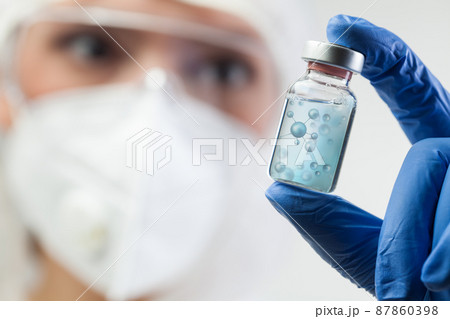 Female lab scientist, microbiologist or biochemist woman holding glass ampoule bottle phial 87860398