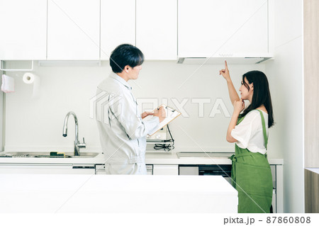 キッチンで話す作業着姿の男性と女性(換気扇・クレーム) キッチンで話す作業着姿の男性と女性(換気扇・クレーム) 87860808