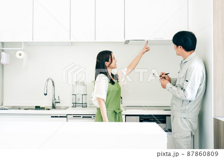 キッチンで話す作業着姿の男性と女性（換気扇） 87860809