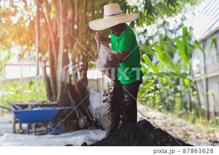 Asian agriculture mixing fertilizer soil for plantation. Asian agriculture mixing fertilizer soil for plantation. 87863628
