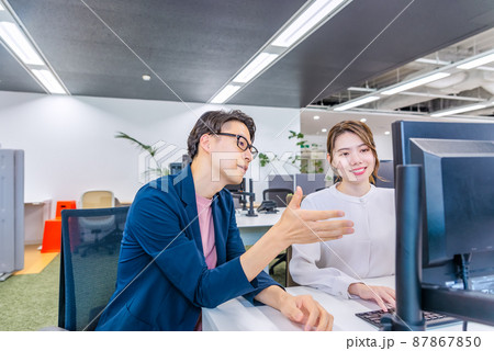 フリーアドレスのオフィスで仕事をするビジネスマンとビジネスウーマン 87867850