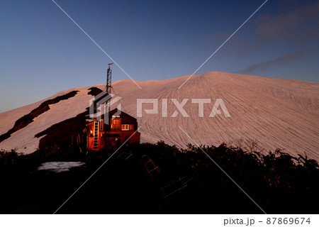 残雪の越後駒ヶ岳山頂のモルゲンロートと駒の小屋 残雪の越後駒ヶ岳山頂のモルゲンロートと駒の小屋 87869674