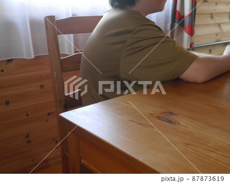 猫背気味に椅子に座る子ども(顔なし) 87873619