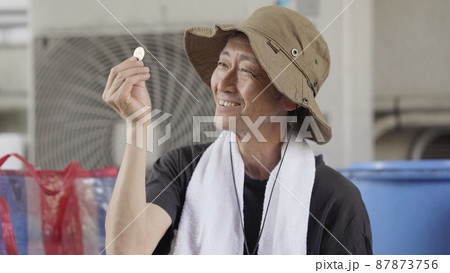 500円硬貨を持つシニア男性 87873756