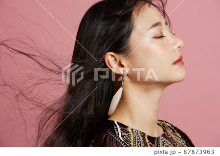 そばかすメイクをした若い女性のピンク背景のポートレートの写真素材