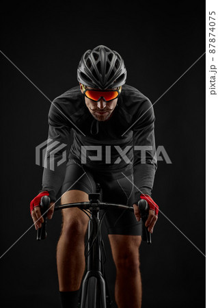 male cyclist riding road bicycle on black background 87874075