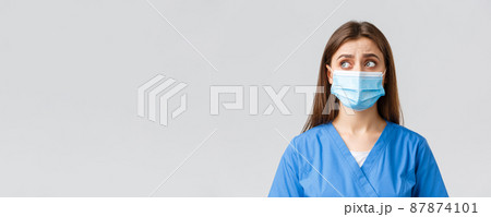 Covid-19, preventing virus, health, healthcare workers and quarantine concept. Skeptical distressed female nurse or doctor in blue scrubs, medical mask, look upper left corner uncertain or puzzled 87874101