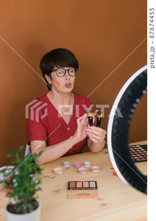 Beauty and cosmetics e-commerce and blogging concept - professional mature female make up artist testing new cosmetics recording video review on cosmetic products at home Beauty and cosmetics e-commerce and blogging concept - professional mature female make up artist testing new cosmetics recording video review on cosmetic products at home 87874455