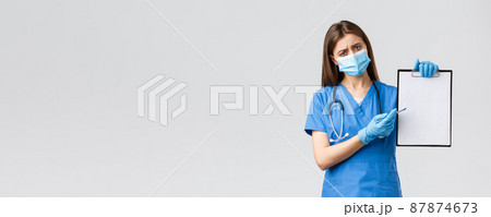 Covid-19, preventing virus, healthcare workers and quarantine concept. Tired concerned female nurse or doctor in blue scrubs, medical mask, explain importance use masks and gloves during coronavirus 87874673