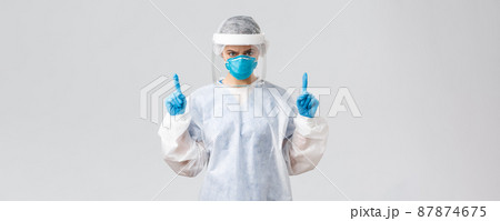 Covid-19, preventing virus, health, healthcare workers and quarantine concept. Angry confident doctor or nurse in respirator, PPE medical suit and gloves, frowning and pointing fingers up 87874675