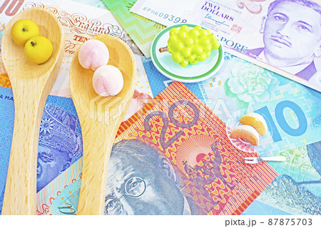世界各国の紙幣とティースプーンの上に置かれた梨と桃のミニチュアと皿の上の葡萄とカットされた桃 87875703
