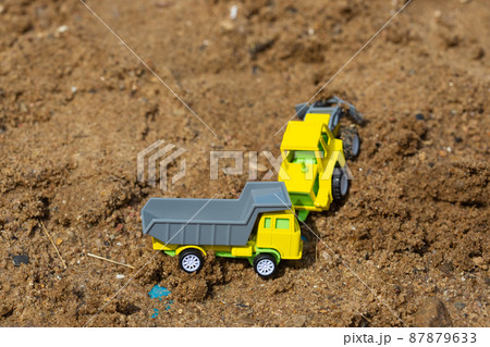 Bright colorful yellow green plastic toy truck in sandbox 87879633