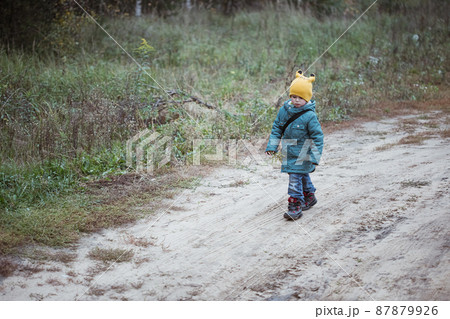 Little caucasian boy in green coat walking in the field autumn time 87879926