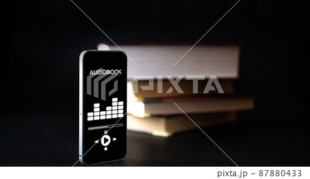 Audiobooks concept. Smartphone screen with audiobook application on paper books black background. Concept of education, library, students. 87880433