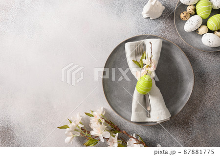 Easter festive table setting with gray plate, spring flowers and green colorful eggs. Easter festive table setting with gray plate, spring flowers and green colorful eggs. 87881775