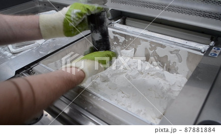Man cleans details printed on industrial 3D printer from white plastic powder 87881884