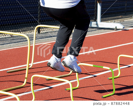 Legs of a boy sumping over mini banana hurdles on a track Legs of a boy sumping over mini banana hurdles on a track 87882448