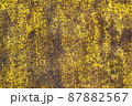 Brown abstract background with acid yellow green red hues. A rust-eaten textured sheet of metal with remnants of paint marks. 87882567