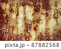 Brown abstract background with beige orange red hues. A weathered, rust-eaten textured sheet of metal with traces of paint residue. 87882568