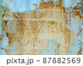 Brown beige abstract background with orange blue hues. A rust-eaten textured sheet of metal with remnants of paint marks. 87882569