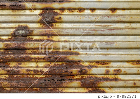 Silver abstract background with pink red brown shades. A rust-eaten ribbed textured sheet of metal with remnants of paint marks. 87882571