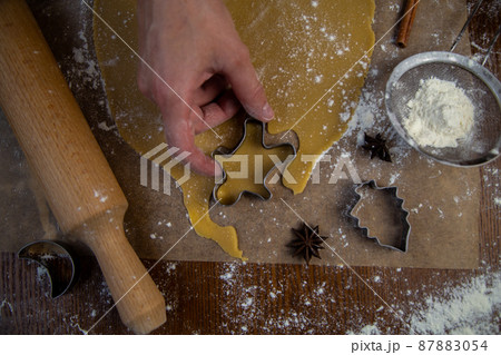 Cookies are cut out of the rolled dough in the form of a man, the pastry chef's hand holds a cookie cutter. High quality photo Cookies are cut out of the rolled dough in the form of a man, the pastry chef's hand holds a cookie cutter. High quality photo 87883054