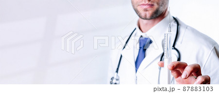 Syringe needle medical injection. Selective focus, doctor hand in blue gloves holding syringe with needle. Hospital white doctor gown, stethoscope. Syringe with flu vaccine with copy space. 87883103