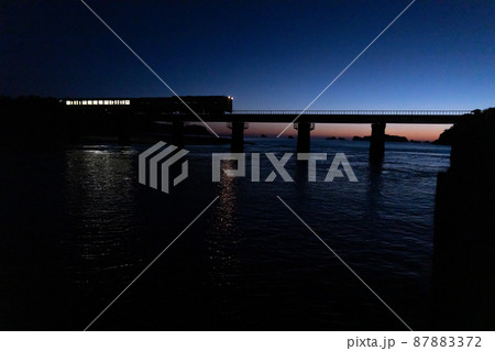 東の空がマジックアワーになった中日南市南郷町の鉄橋を走行するJR九州ローカル線日南線のキハ40 87883372