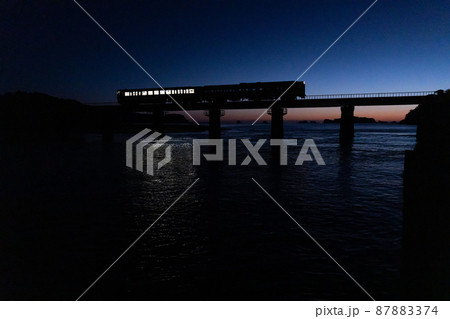 東の空がマジックアワーになった中日南市南郷町の鉄橋を走行するJR九州ローカル線日南線のキハ40 87883374