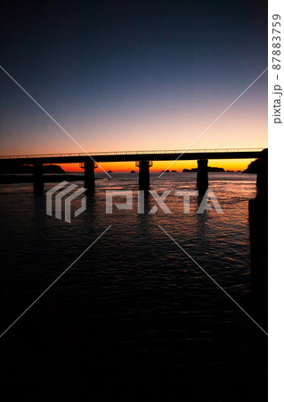 東の空がマジックアワーになった中日南市南郷町の鉄橋を走行するJR九州ローカル線日南線のキハ40 87883759