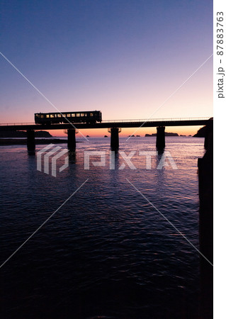 東の空がマジックアワーになった中日南市南郷町の鉄橋を走行するJR九州ローカル線日南線のキハ40 87883763