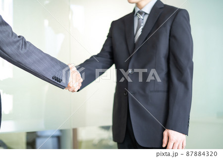握手をするスーツ姿のビジネスマン　顔なし 87884320