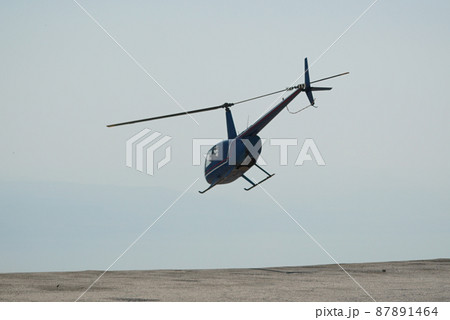 Blue helicopter flying in grey cloudy skies 87891464