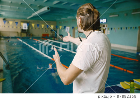 Coach practise with swimmer in the indoor swimming pool Coach practise with swimmer in the indoor swimming pool 87892359